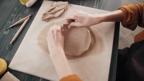 Young Adult Shaping Clay Pottery on Wooden Table