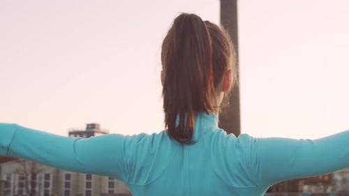 Woman Stretching on a Rooftop at Sunset