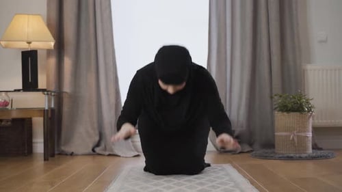 Porträt einer jungen muslimischen Frau in schwarzer Tracht und Hijab, die zu Hause betet, Schöne Frau