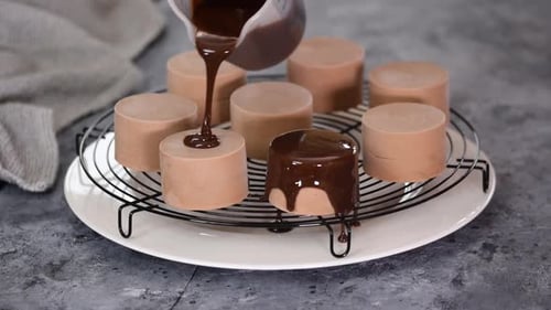 Chocolate Being Poured onto Mousse Cakes