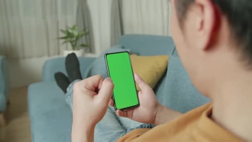 Male Celebrating While Using Smartphone With Green Screen Display In Living Room