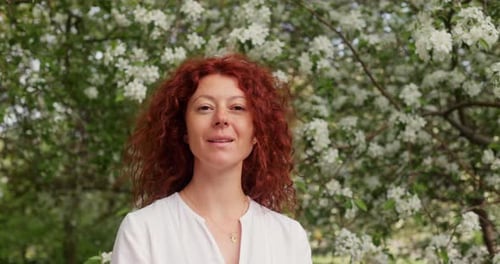 Woman Smiles Among White Blossoms in Springtime
