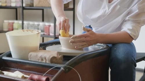 Woman Working on Potters Wheel Making Dishes with Their Own Hands. Close-up Photo of Dirty Hands