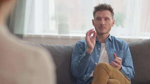 Man Talking on Couch Indoors