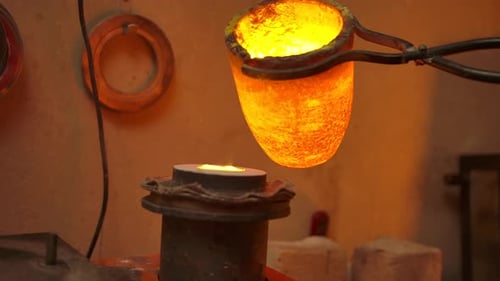 Unerkennbarer Meister gießt heißes Metall mit einer speziellen Zange in die Form