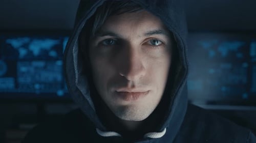 Close Up Portrait of Hacker Programmer in Black Hoody at Background of Cyber Security Center Filled