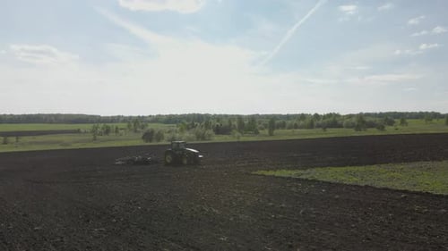 Landwirtschaftlicher grüner großer Traktor pflügt auf dem Feld.