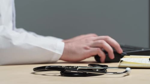 Doctor Typing with Stethoscope on Desk