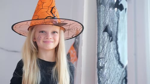 Smiling Girl in Witch Costume with Halloween Decorations