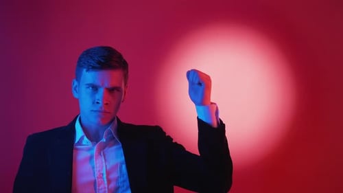Man in Suit Raises Fist in Colorful Studio