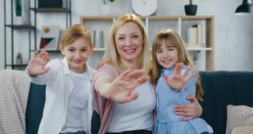 Madre sonriente y su lindo y alegre hijo e hija que están sentados en el sofá de casa