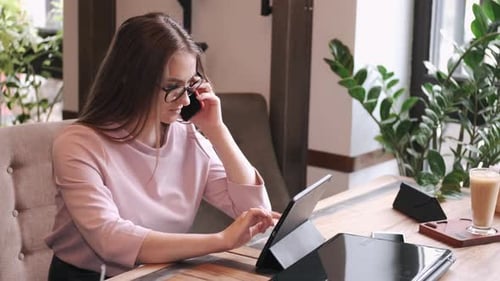 Young Woman Talking on Phone Using Tablet