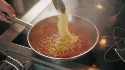Chef Adding Spaghetti to Red Tomato Sauce