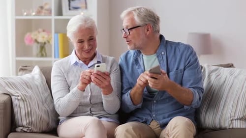 Senior Couple Using Cell Phones Together on Sofa