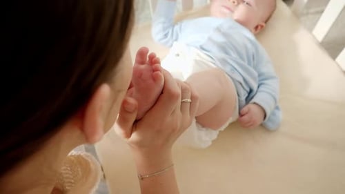 Mother gently holding baby's feet in crib