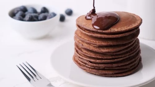 Chocolate Syrup Being Poured Onto Stack Of Pancakes