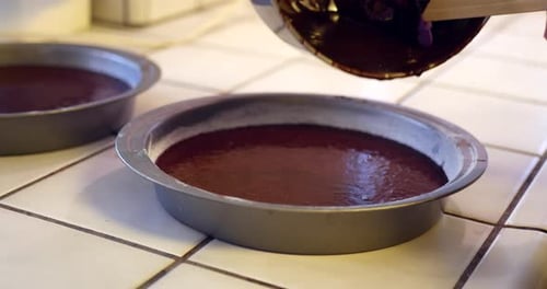 Pouring Delicious Brownie Batter Into Cake Pans