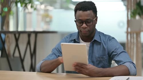 Attractive Young African Man Using Tablet in Modern Office
