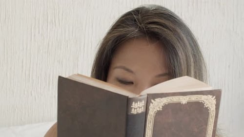 Front View of Pretty Woman Reading Book and Looking at Camera