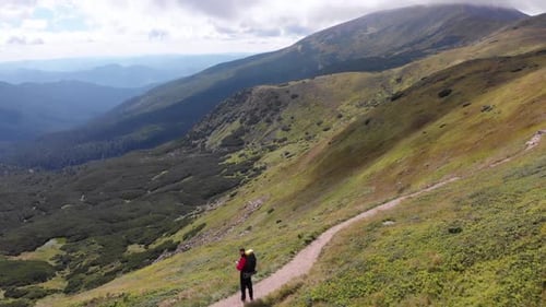 Aerial View of a Traveler with Backpack Climbing Along Mountain Slope. Epic Shot