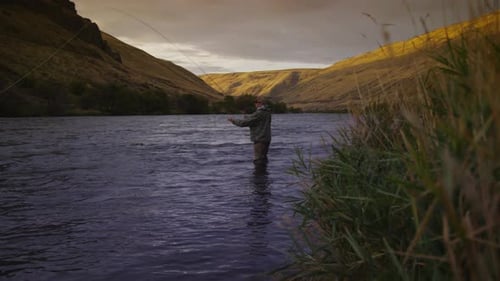 Man fly fishing in beautiful river at sunrise