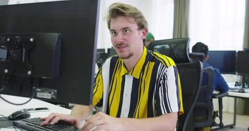 Businessman Working at His Desktop Computer Sitting at His Desk in the Open Space Startup Office