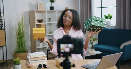 Bloguera con cajas de regalo en las manos durante la grabación de un nuevo vlog para una audiencia de Internet