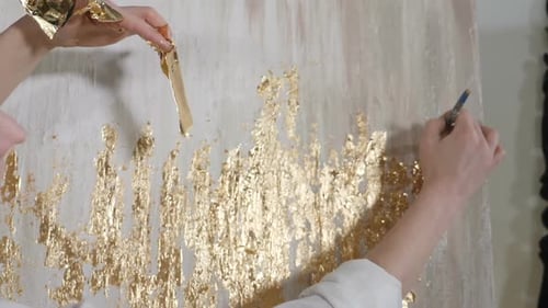 Attraktive Künstlerin, die Blattgold auf ihr Kunstwerk anwendet