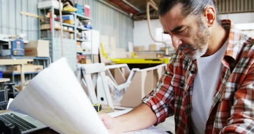 Man Reviews Construction Plan in Workplace