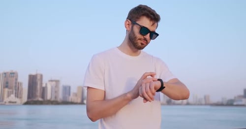 Young Man Uses Smartwatch with City Background