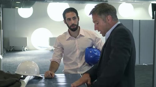 Two Men Discuss Construction Project in Modern Office