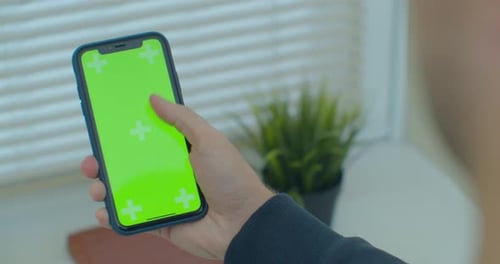 Man Using Vertical Smartphone with Green Screen. Close-up Shot of Man's Hands with Mobile Phone