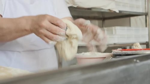 Baker Shaping Dough in Kitchen with Flour
