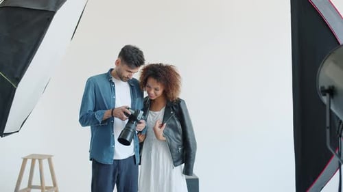 Model and Photographer Watching Photos on Digital Camera Smiling in Studio