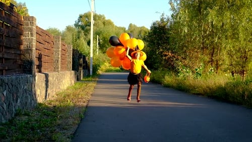 Girl Runs with Halloween Balloons in Costume