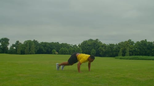 Active Sporty Fit Afro-Américain faisant de l'entraînement Burpees sur Green Field