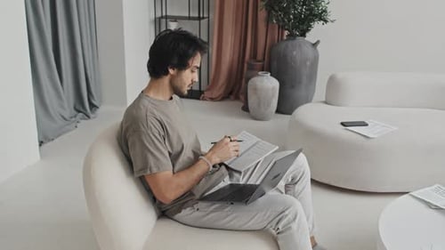 Freelancer macht sich Notizen im Wohnzimmer