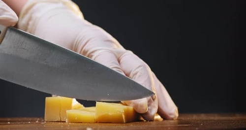 Hands With Gloves Cutting Cheese Into Cubes