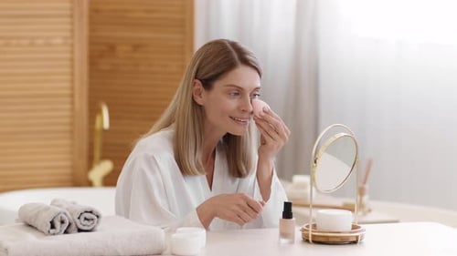 Woman Applies Makeup in Bright Bathroom