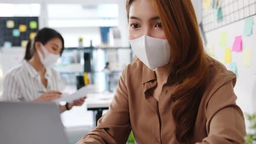 Businesspeople using computer presentation meeting and wear face mask back in office