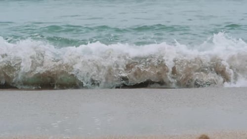 Sea Waves Crash Over the Sand Beach on Cloudy Day
