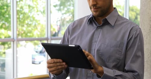 Man Smiling While Using Tablet in Modern Office