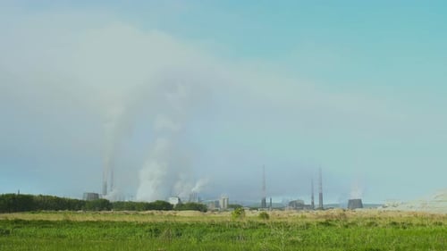 Pipas de fábrica de humo en campo verde