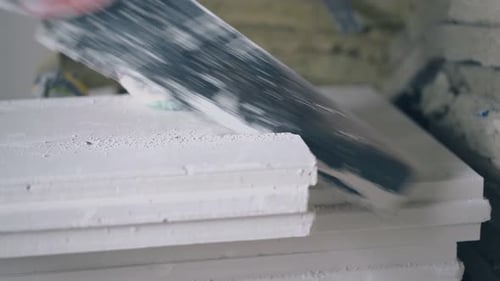 Hand Saw Cutting Stack of Drywall Boards