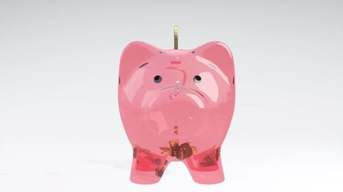 Coins Fall Into a Pink Glass Piggy Bank - a Symbol of Wealth, Frugality and Effective Investment