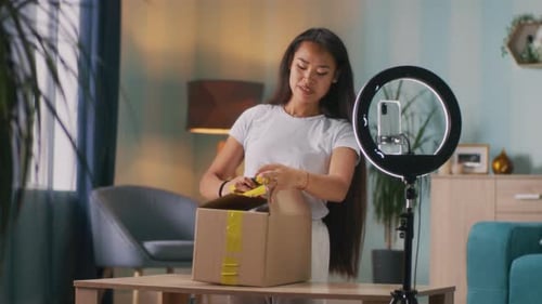 Woman Opens Package with Ring Light and Smartphone