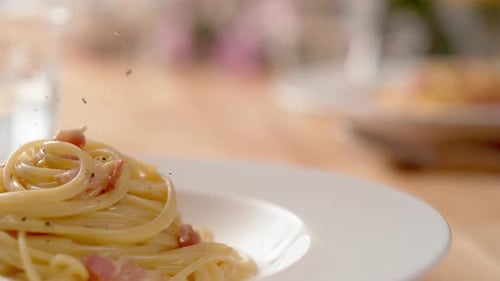 Close Up of Seasoning Spaghetti Carbonara With Pepper