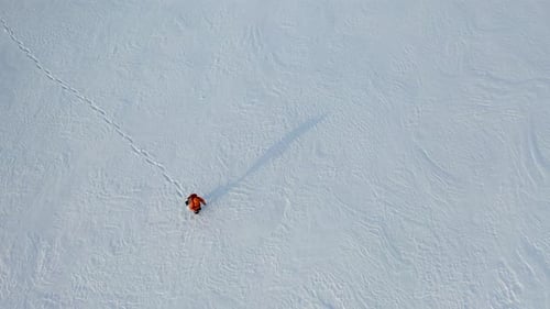Lone Traveler with a Backpack Walks Through the Snowy Desert