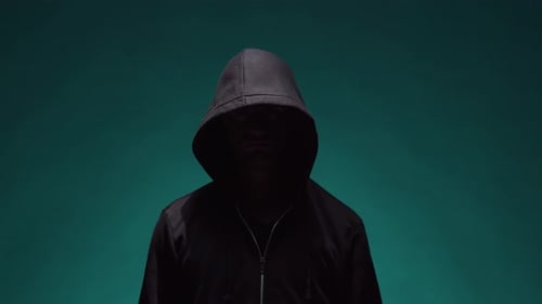 Mysterious Hooded Figure Raising Hand in the Shadows