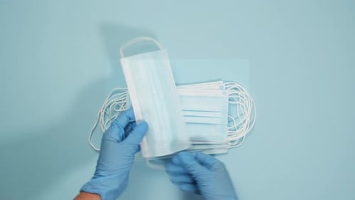 Stack of Surgical Masks Held by Gloved Hands